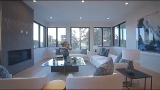 Still from the tour: living room with corner glazing and a linear gas fireplace.