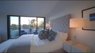 Still from the tour: master bedroom at sunset with balcony access.